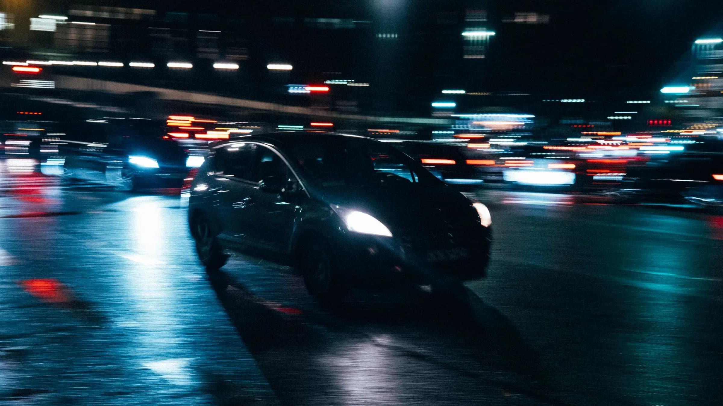 Traffic on a wet city street at night, the headlights and tail lights drawn out into streaks.