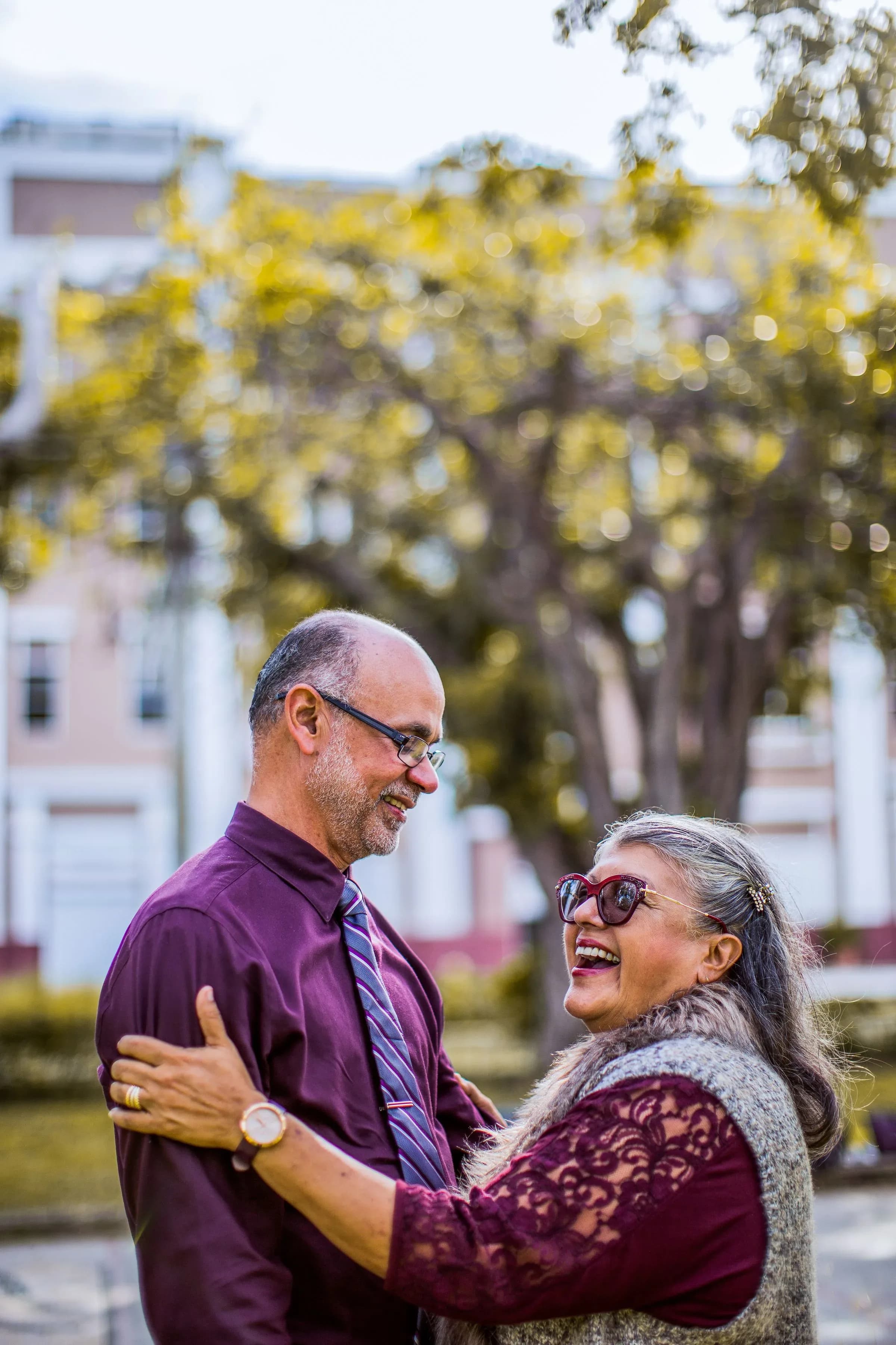 A couple in their sixties laughing together in a park.