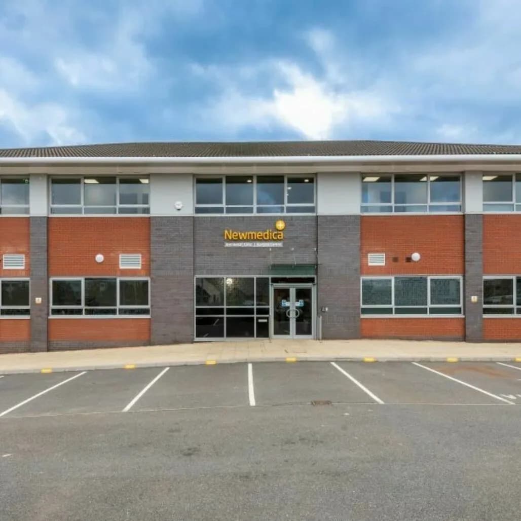 The exterior of the Newmedica eye clinic at Grove Park, Leicester, a two-storey brick building with parking directly outside.