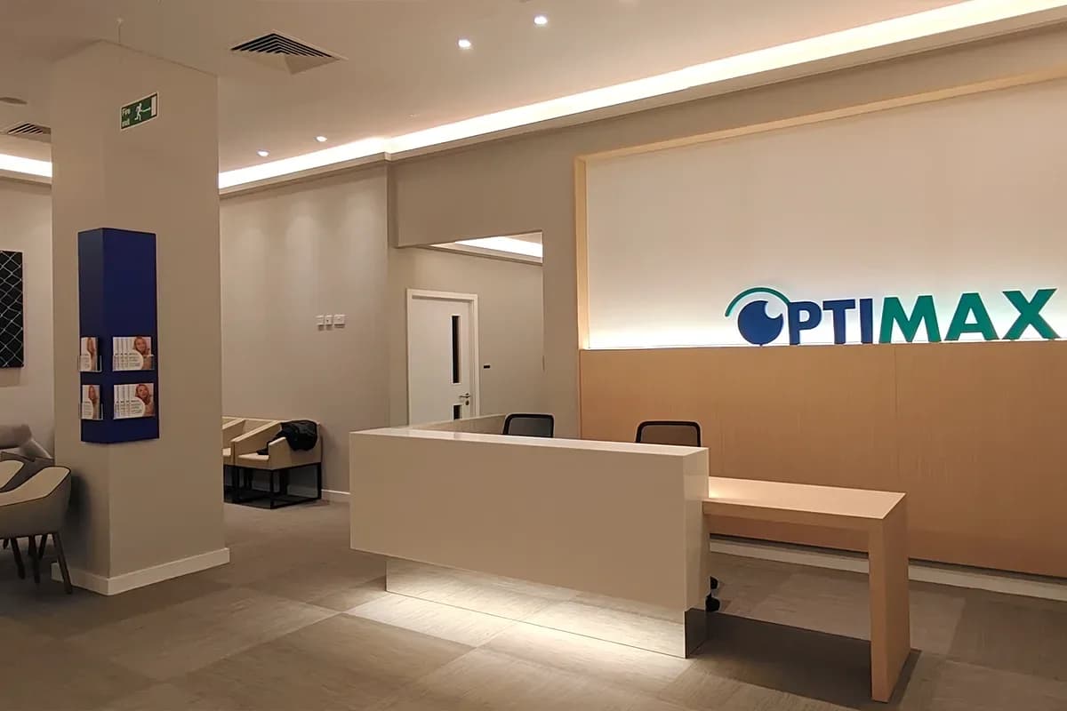 The reception area inside the Optimax clinic in the Tower Building, Liverpool, with the Optimax name lit on the wall behind the desk.